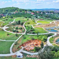 Malowniczy park w kielecczyźnie z krętymi ścieżkami, stawami i skalistym wykopem.