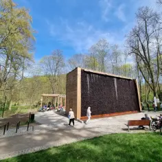 Spacer po tężniach w Kudowie-Zdroju to świetny pomysł na wieczór. Ludzie odpoczywają, podziwiając architekturę i zieleń.
