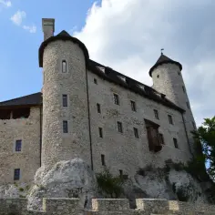 Kamienny zamek na skale, jedna z głównych atrakcji Bobolic, z wieżami i kamiennymi murami pod błękitnym niebem.