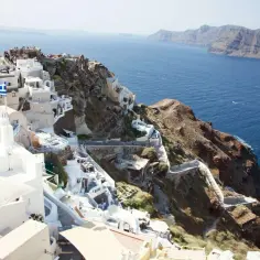 Santorini, Grecja. Białe domy na klifie, grecka flaga i błękitne morze. Ciekawe miejsca i widoki.