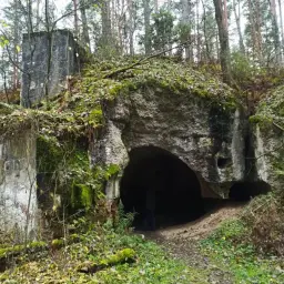 Ruiny twierdzy Osowiec, porośnięte mchem i liśćmi, zapraszają na zwiedzanie. Wejście do bunkra w lesie.