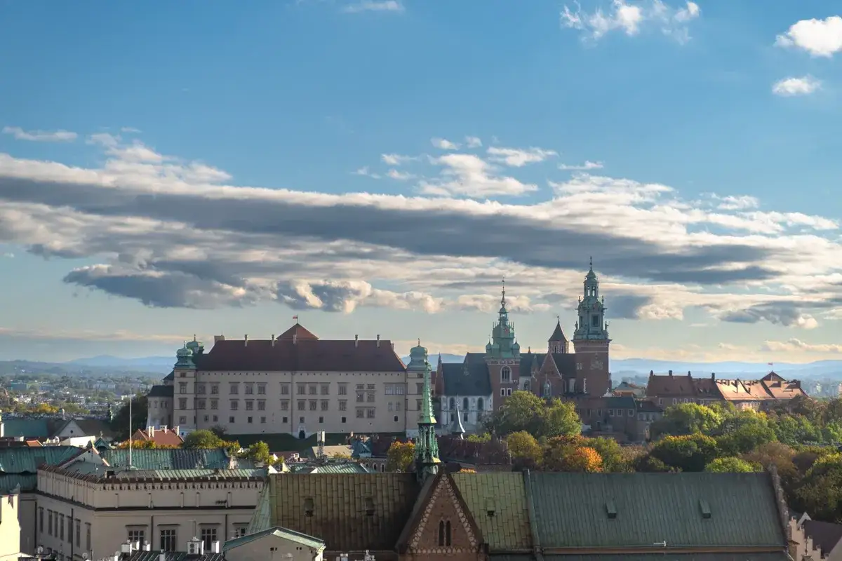 Wawel i jego wieże na tle błękitnego nieba z chmurami. To jedno z tych fajnych miejsc w Krakowie, które warto zobaczyć.