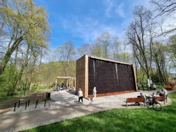 Spacer po tężniach w Kudowie-Zdroju to świetny pomysł na wieczór. Ludzie odpoczywają, podziwiając architekturę i zieleń.