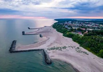 Jarosławiec molo chroni plażę przed falami. Widok z lotu ptaka na morze, plażę i zabudowania.